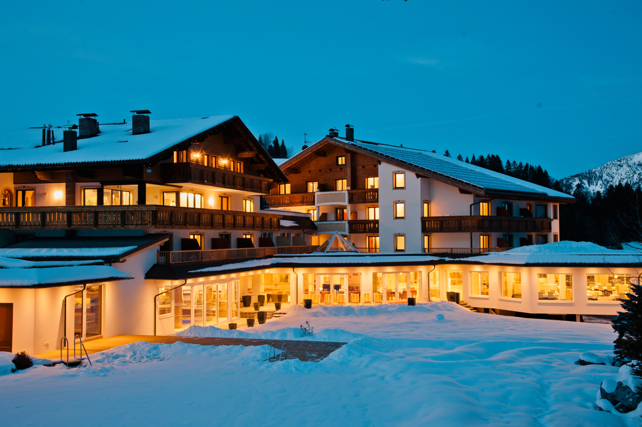 Alpinresort Schillerkopf in Bürserberg – Beleuchtetes Hotel im Schnee bei Dämmerung | Wellnesshotel Vorarlberg