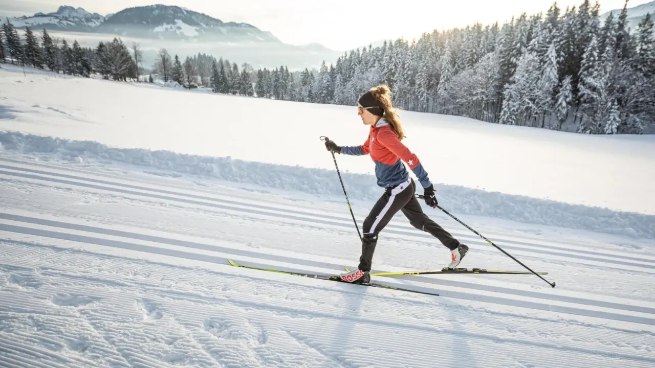 Langläuferin auf präparierter Loipe vor verschneiter Berglandschaft am Vitalhotel Berghof.