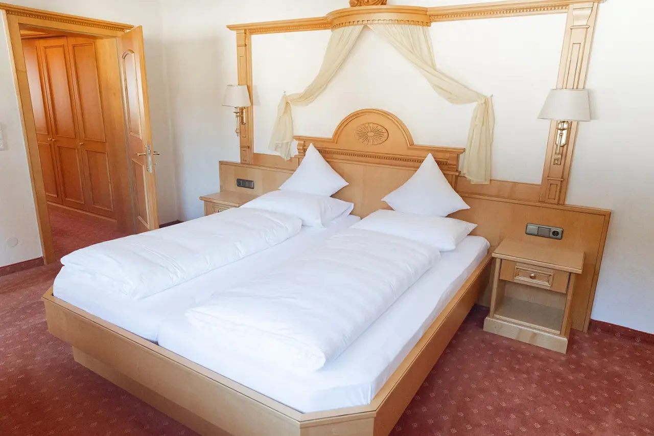 Gemütliches Doppelzimmer mit hellem Holzmobiliar und weißer Bettwäsche im Vitalhotel Berghof.