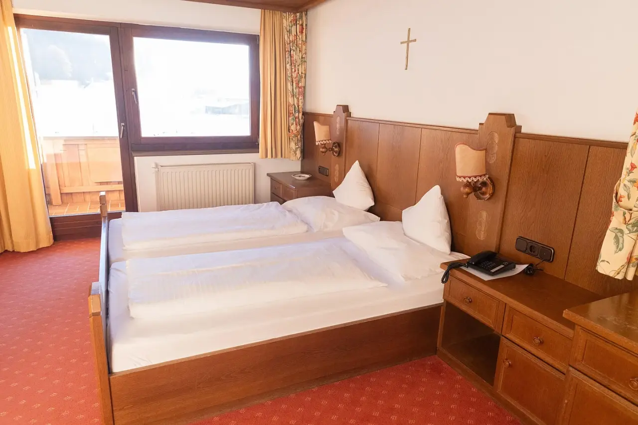 Gemütliches Doppelzimmer mit Holzeinrichtung und Balkon im Vitalhotel Berghof.