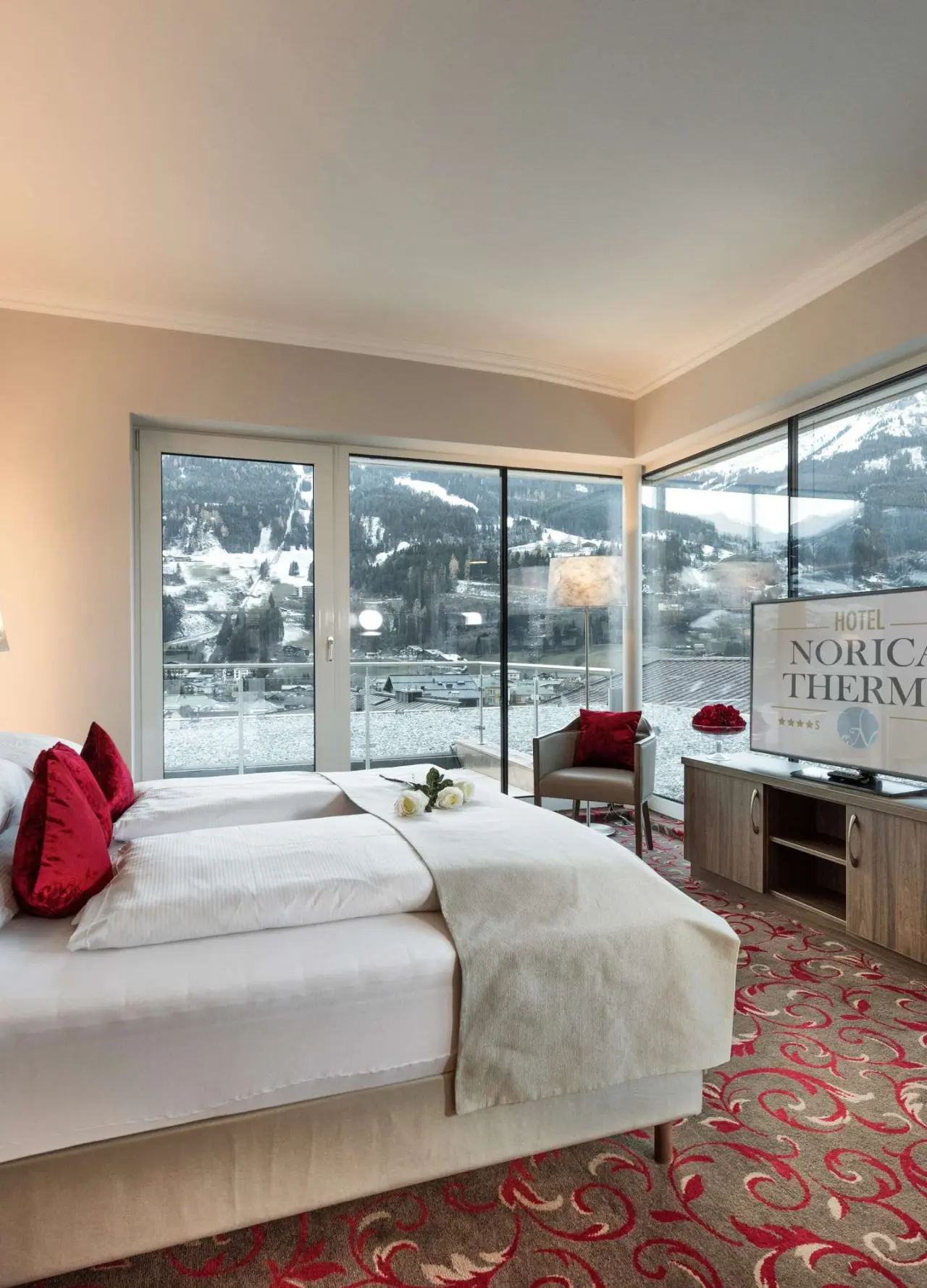 Komfortables Doppelzimmer im Hotel Norica mit Panoramablick auf die verschneite Berglandschaft und gemütlichem Sitzbereich.