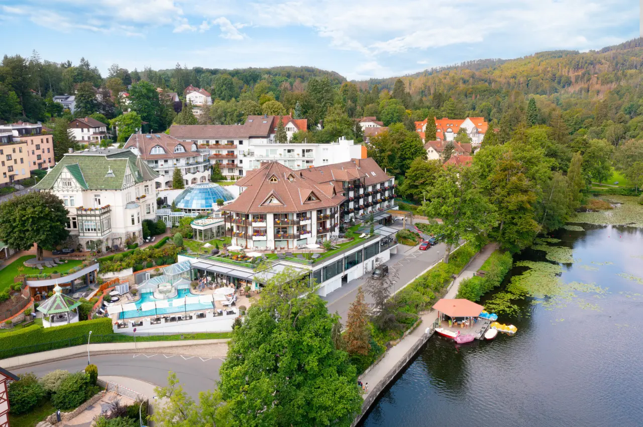 Luftaufnahme des Hotel Romantischer Winkel - RoLigio® & Wellness Resort mit Poolanlage, See und umliegender Natur.