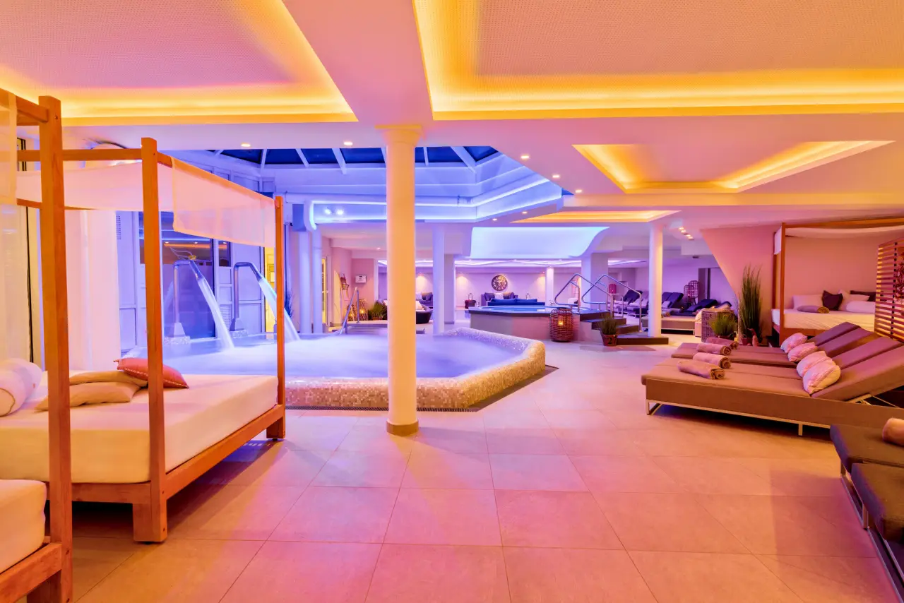 Grosszügiger Spa-Bereich mit farbiger Beleuchtung, Pools und Entspannungsliegen im Hotel Romantischer Winkel.