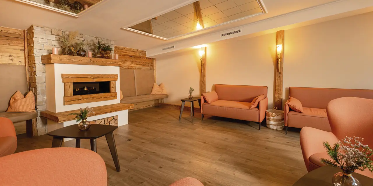 Gemütliche Hotellounge mit Kamin, Holzvertäfelung und bequemen Sitzgelegenheiten im Aktiv- & Vitalhotel Bergcristall.