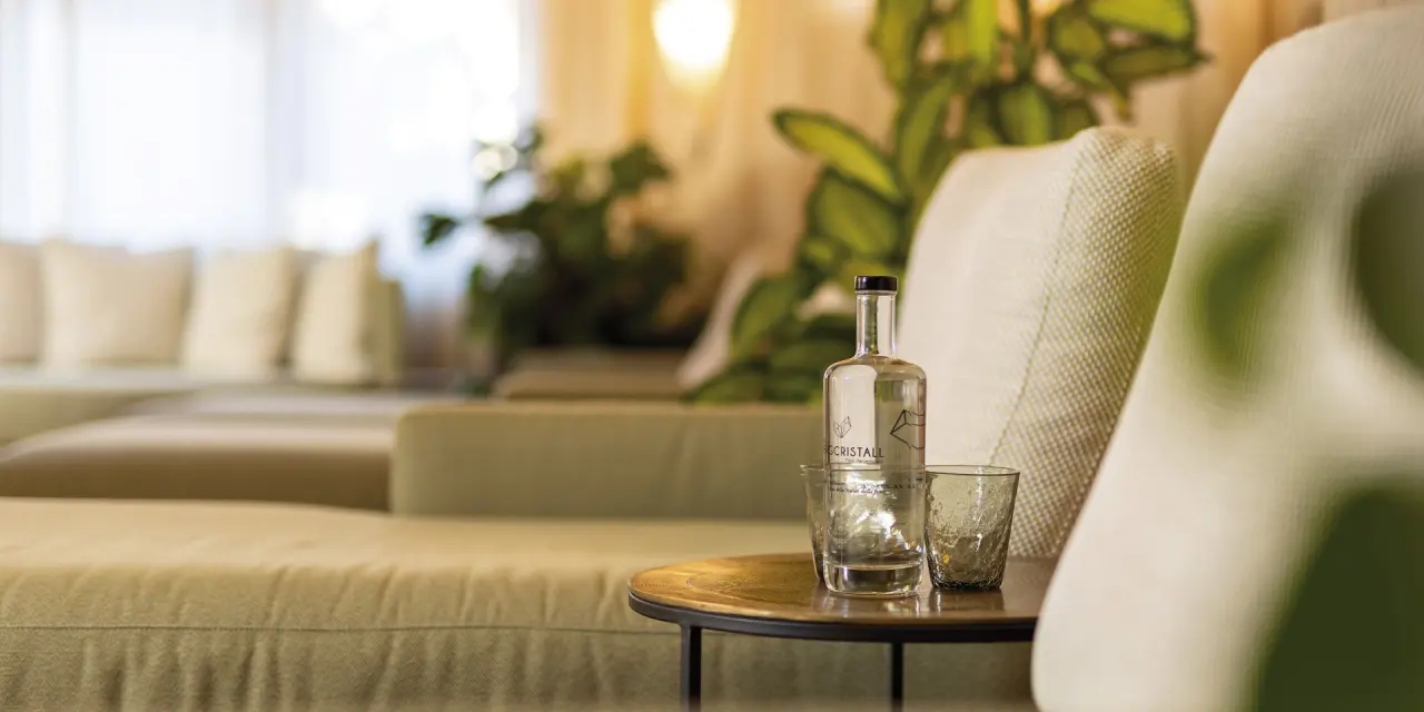 Erfrischendes Wasser mit Hotel-Branding auf Beistelltisch in der gemütlichen Lounge des Aktiv- & Vitalhotel Bergcristall.