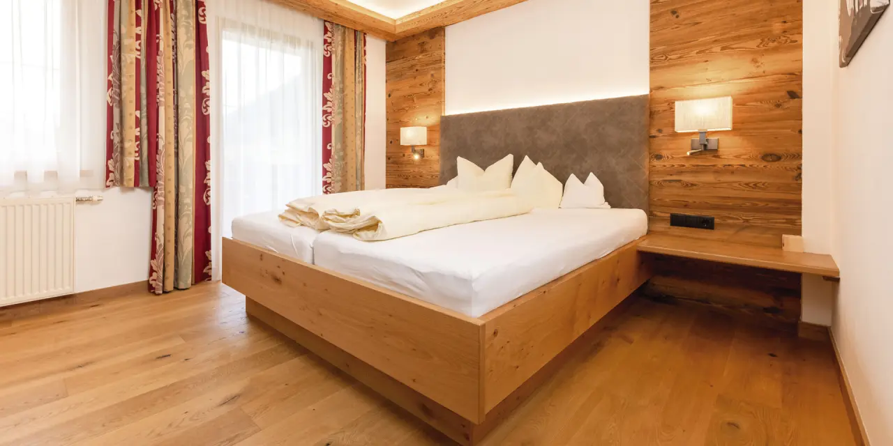 Gemütliches Doppelzimmer im Aktiv- & Vitalhotel Bergcristall mit Holzelementen, bequemen Betten und Tageslicht.
