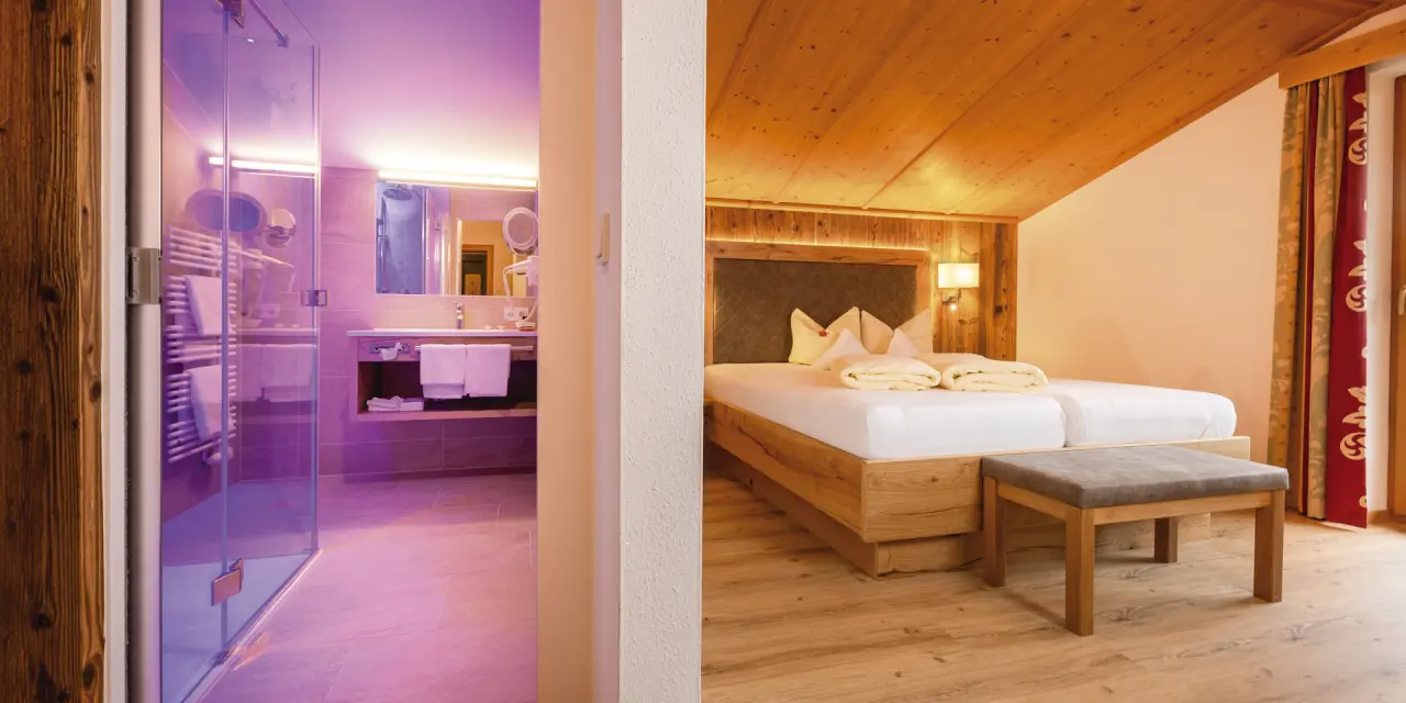 Gemütliches Doppelzimmer mit Holzelementen und modernem Bad mit lila Beleuchtung im Aktiv- & Vitalhotel Bergcristall.