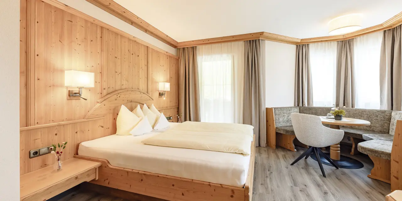 Gemütliches Doppelzimmer im alpenländischen Stil mit Holzelementen und Sitzecke im Aktiv- & Vitalhotel Bergcristall.