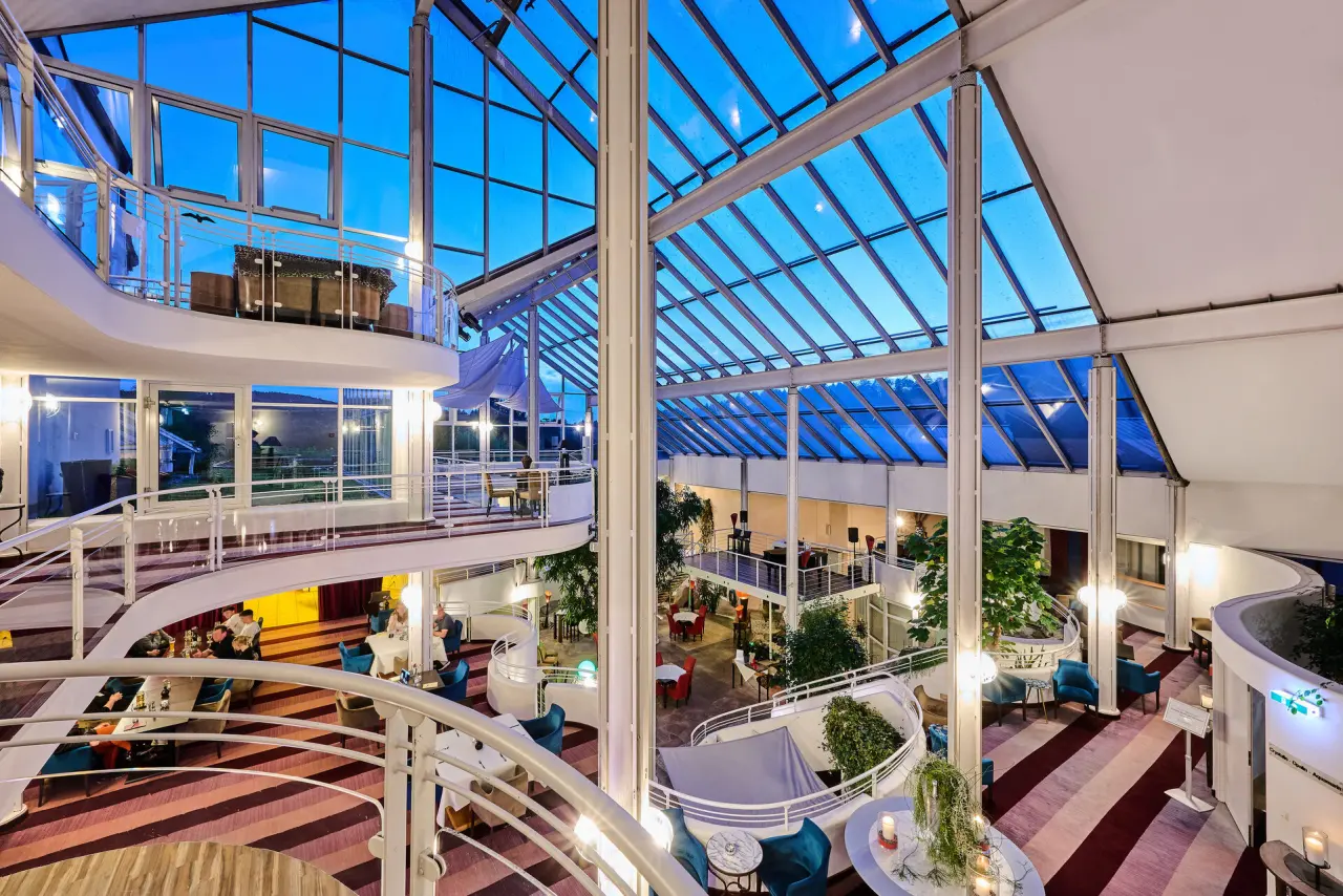 Modernes, lichtdurchflutetes Atrium und Lobbybereich des Hotel Wutzschleife mit Glasdach und Sitzgelegenheiten.