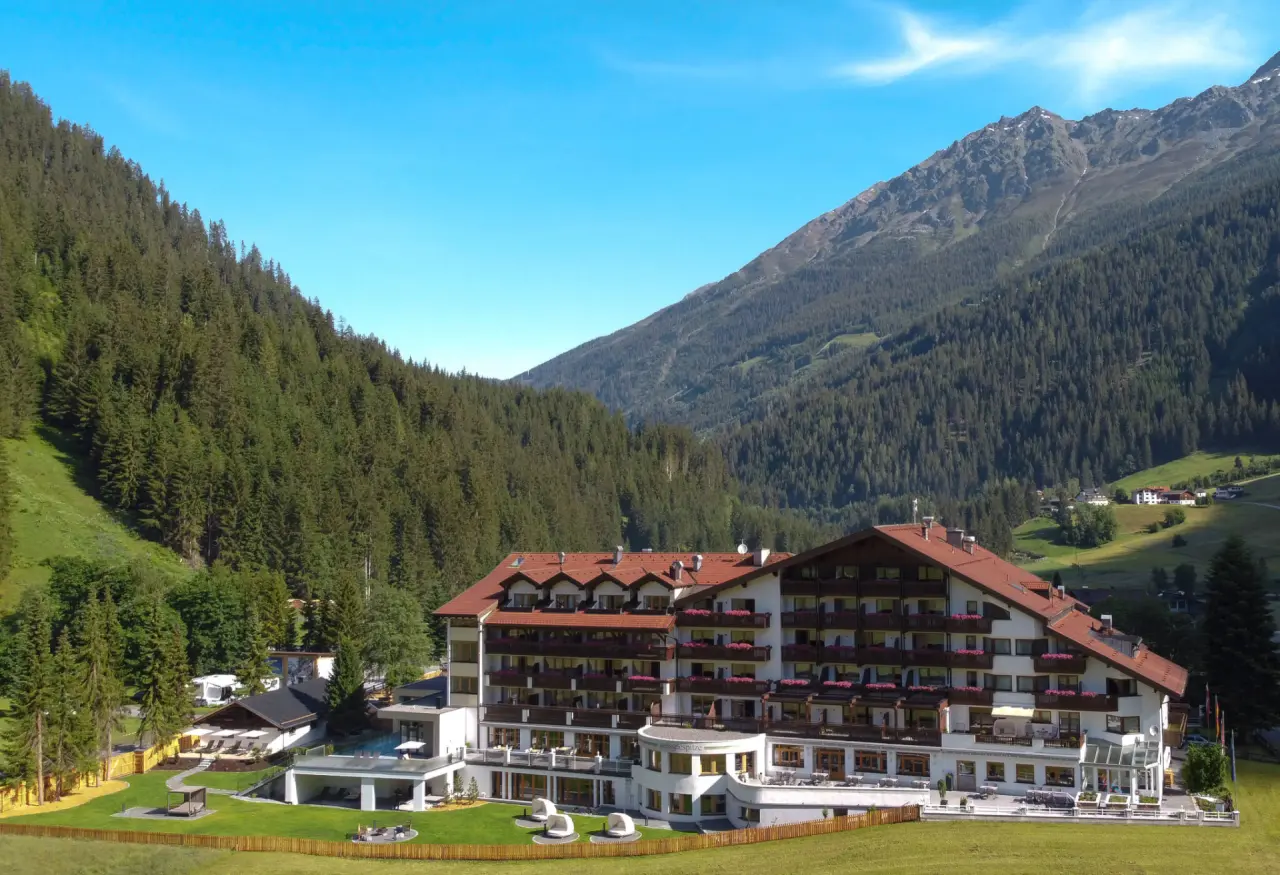 Panoramablick auf das Hotel Weisseespitze in den Tiroler Alpen mit umliegenden Wäldern und Bergen.