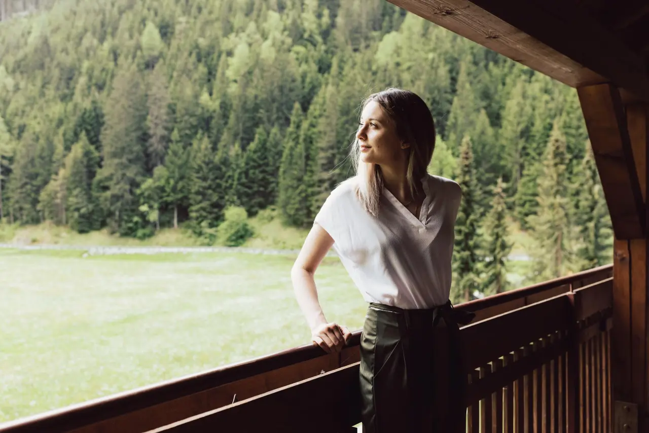 Hotel Weisseespitze in Kaunertal – Frau genießt den Ausblick vom Hotelbalkon auf den Wald | Wellnesshotel Tirol