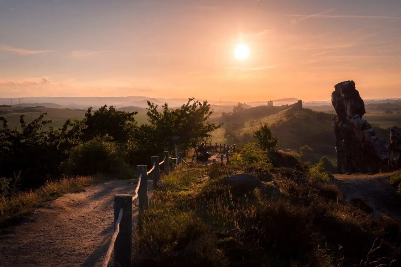 Sonnenuntergang über der hügeligen Landschaft mit Felsformationen nahe dem Hotel & Spa Wasserschloss Westerburg.