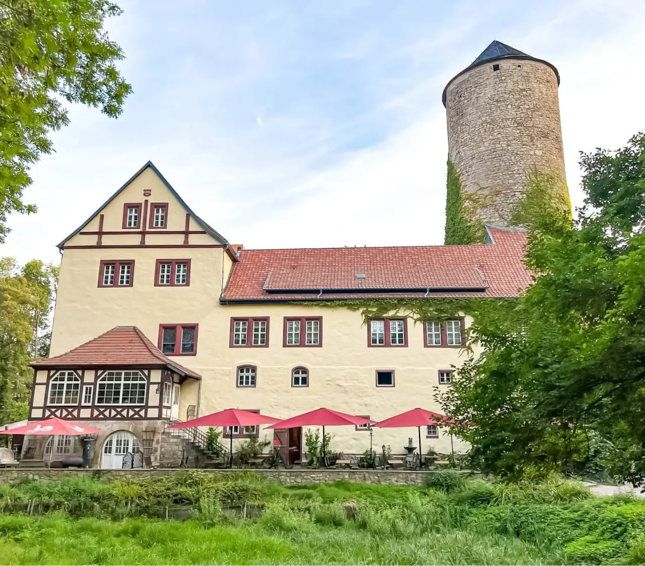 Historisches Hotel & Spa Wasserschloss Westerburg mit Turm, Fachwerk und Terrasse im Grünen.