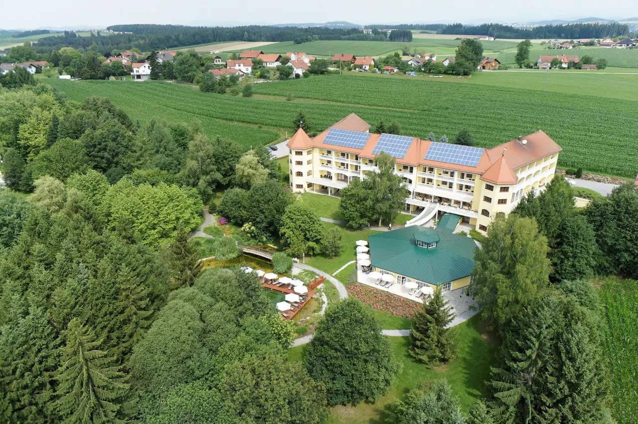 Luftaufnahme des Parkschlössl zu Thyrnau mit Hotelgebäude, weitläufigem Garten, Badeteich und umliegender Naturlandschaft.