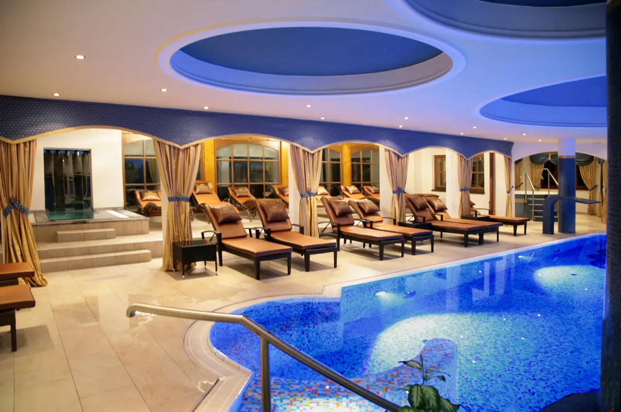 Eleganter Innenpool mit Mosaikfliesen und bequemen Liegen im Wellnessbereich des Parkschlössl zu Thyrnau.