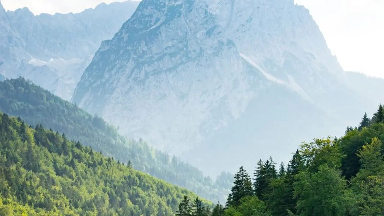 Majestätisches Bergpanorama mit grünen Wäldern in der Umgebung des Riessersee Hotels.