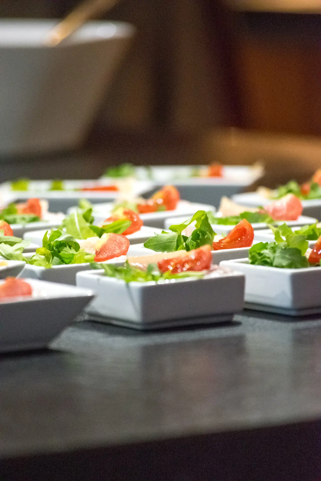 Kleine Vorspeisen mit Rucola und Tomaten in weißen Schälchen auf einem Buffet im Riessersee Hotel.