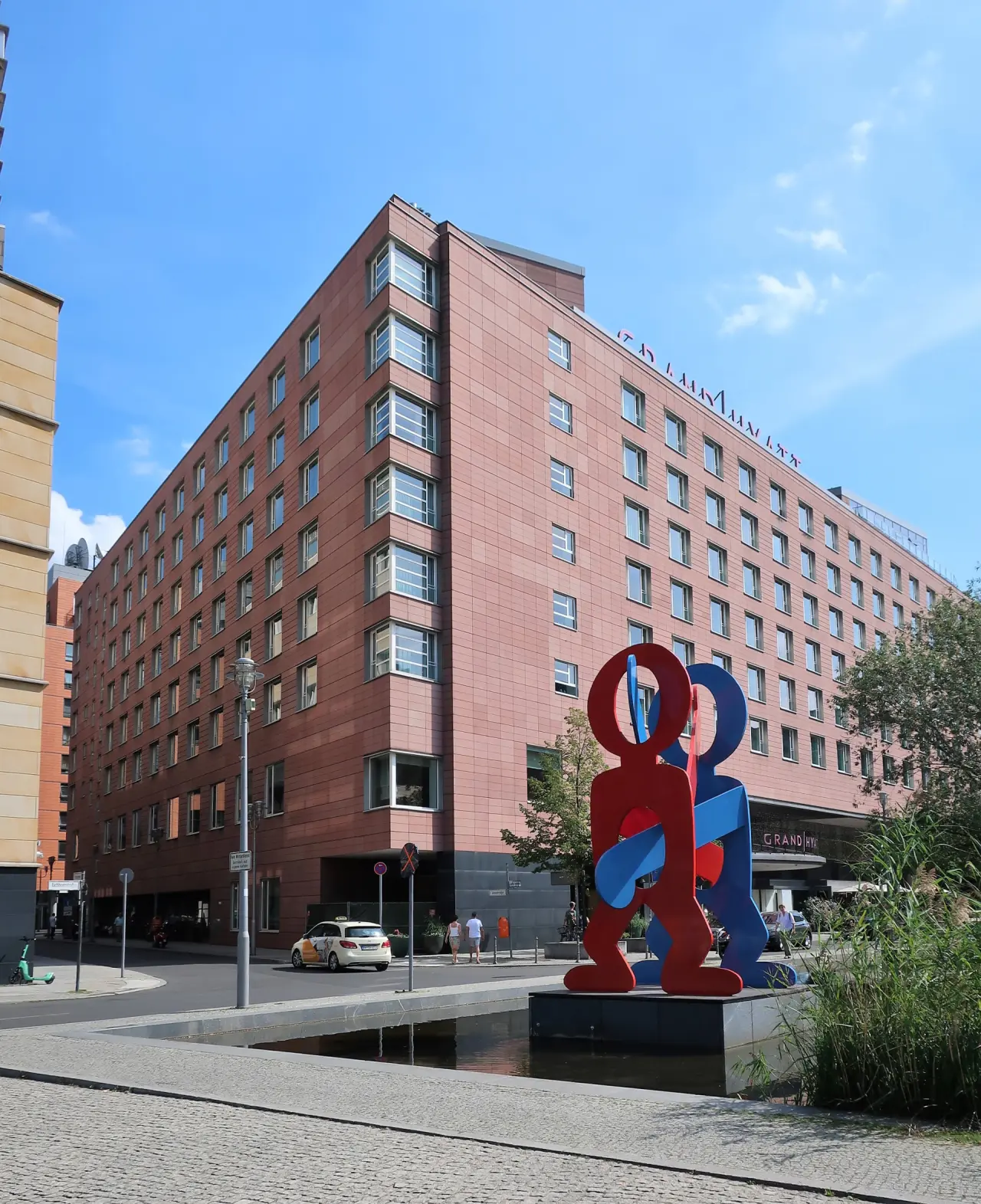Aussenansicht des Grand Hyatt Berlin am Potsdamer Platz mit moderner Skulptur und Wasserbecken.
