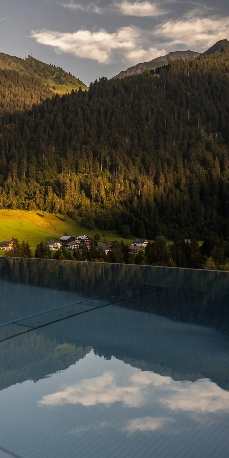 Hotel Erlebach in Riezlern – Spiegelung der Berglandschaft im Infinity-Pool | Wellnesshotel Vorarlberg