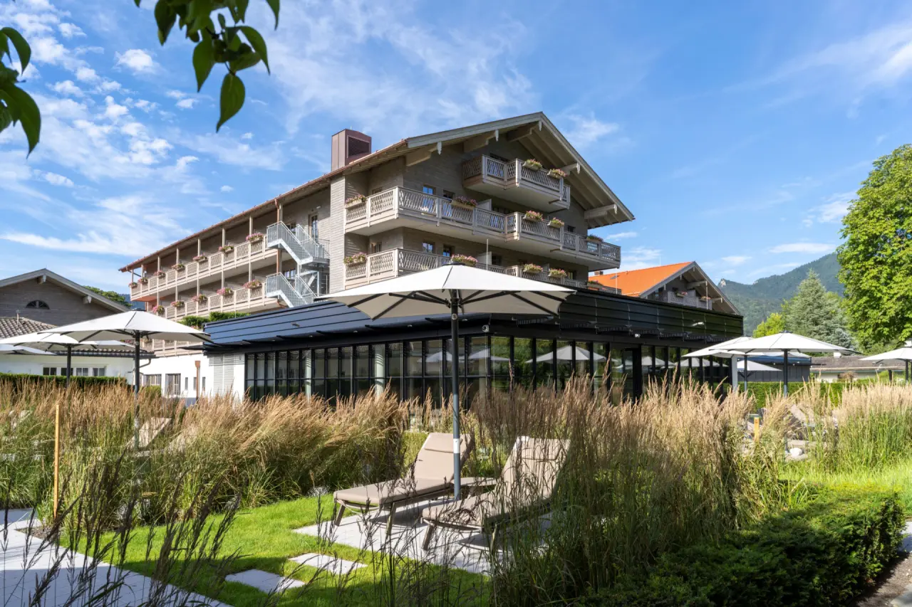 Park-Hotel Egerner Höfe Aussenansicht mit traditioneller Architektur, gepflegtem Garten, Liegestühlen und Bergkulisse.