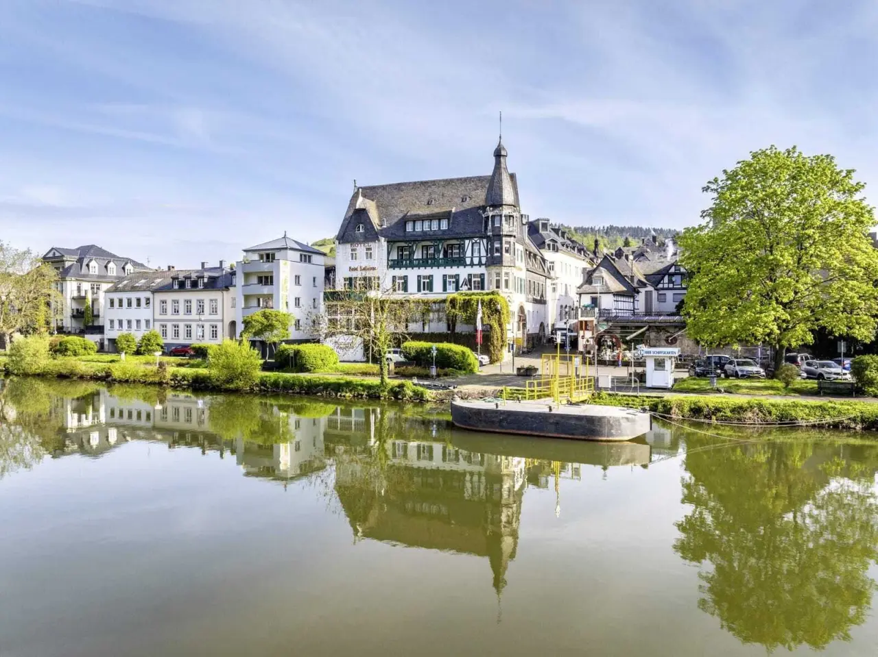 Romantik Jugendstilhotel Bellevue an der Mosel mit historischer Architektur, umgeben von Grün und Spiegelung im Fluss.