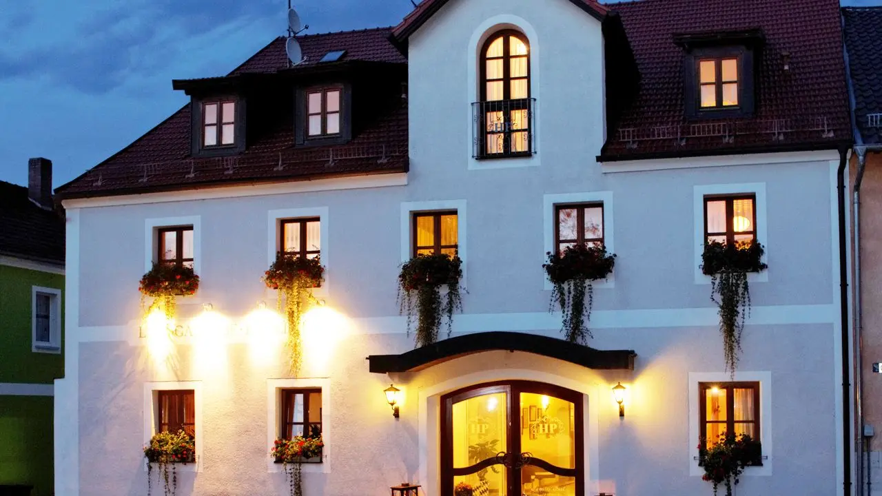 Einladende Aussenansicht des Zedernhof Gesundheits- und Wellnesshotels bei Abenddämmerung mit beleuchteten Fenstern und Blumenkästen.