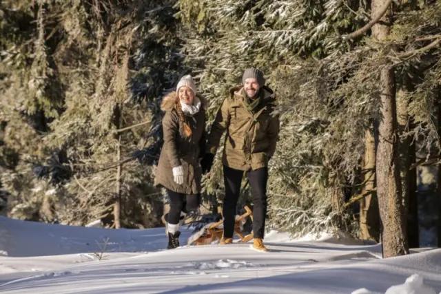 Hotel Sonnenhof in Lam – Paar beim Winterwandern und Schlittenfahren im Wald | Wellnesshotel Bayerischer Wald