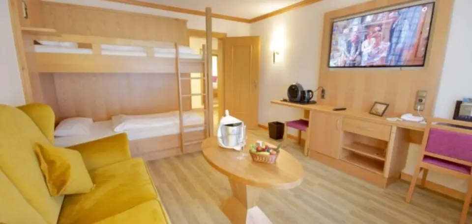 Hotel Sonnenhof in Lam – Helles Familienzimmer mit Stockbett und gelbem Sofa | Wellnesshotel Bayerischer Wald