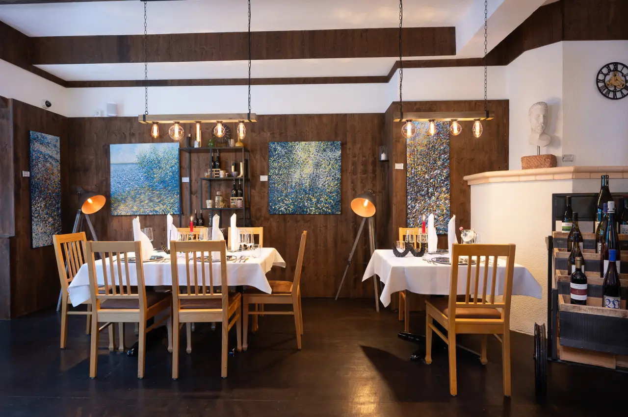 Gemütlicher Restaurantbereich im Vitalhotel Sonneck mit Holzwänden, modernen Bildern und elegant gedeckten Tischen.