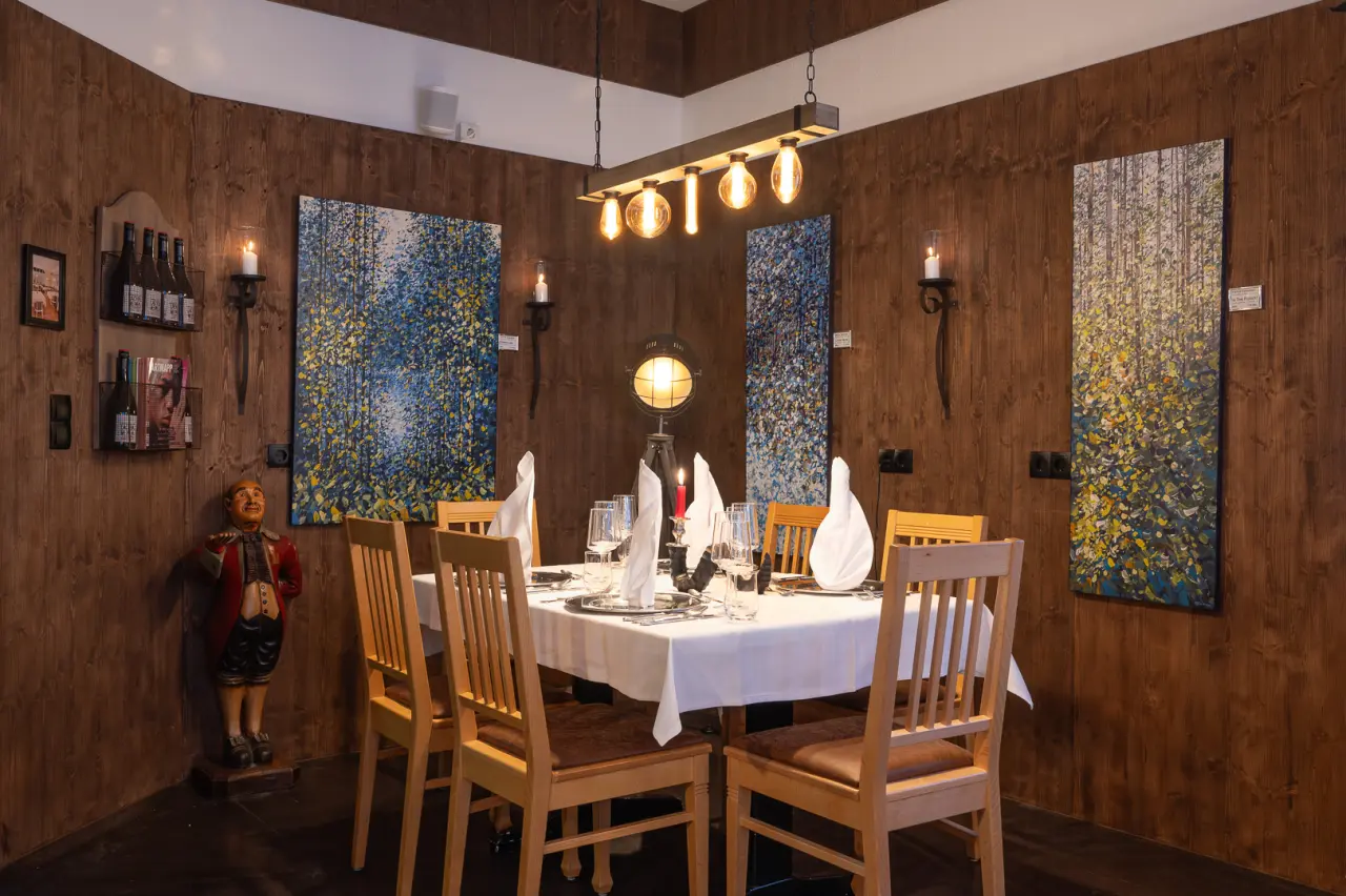 Gemütlicher Restaurantbereich im Vitalhotel Sonneck mit rustikaler Holzvertäfelung, festlich gedecktem Tisch und warmem Licht.