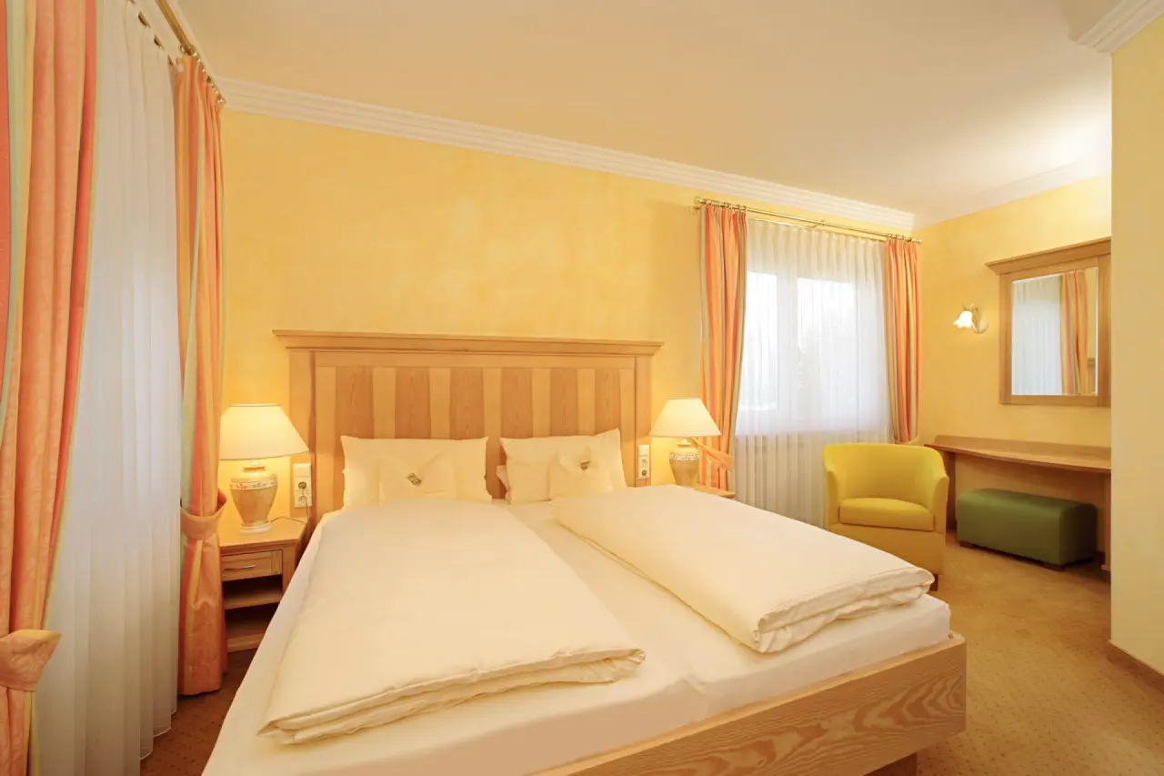 Gemütliches Doppelzimmer mit hellem Holz und warmen Farben im Vitalhotel Sonneck.