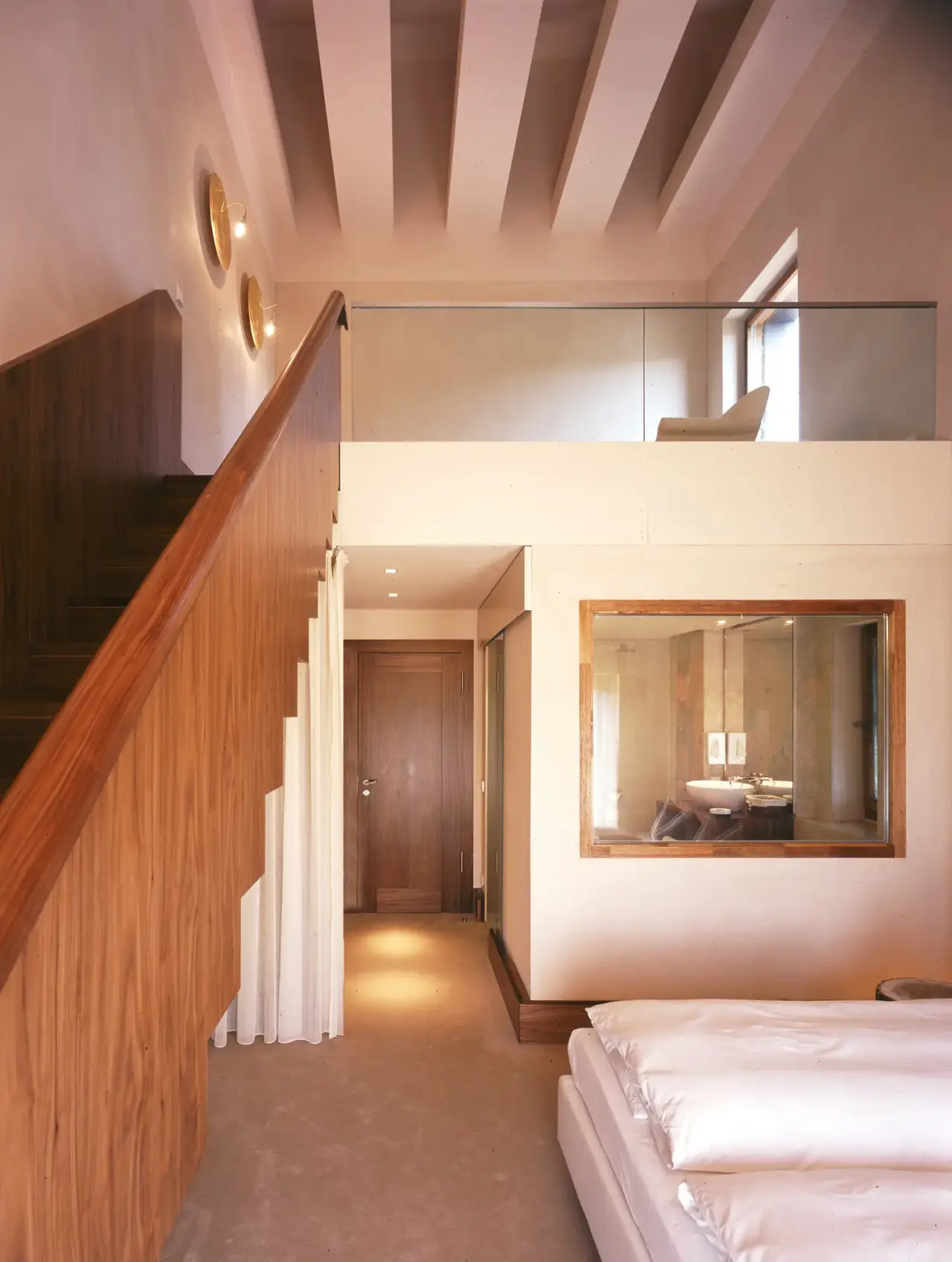 Geräumiges Hotelzimmer mit Holztreppe und Blick ins Bad im Seehotel am Neuklostersee.