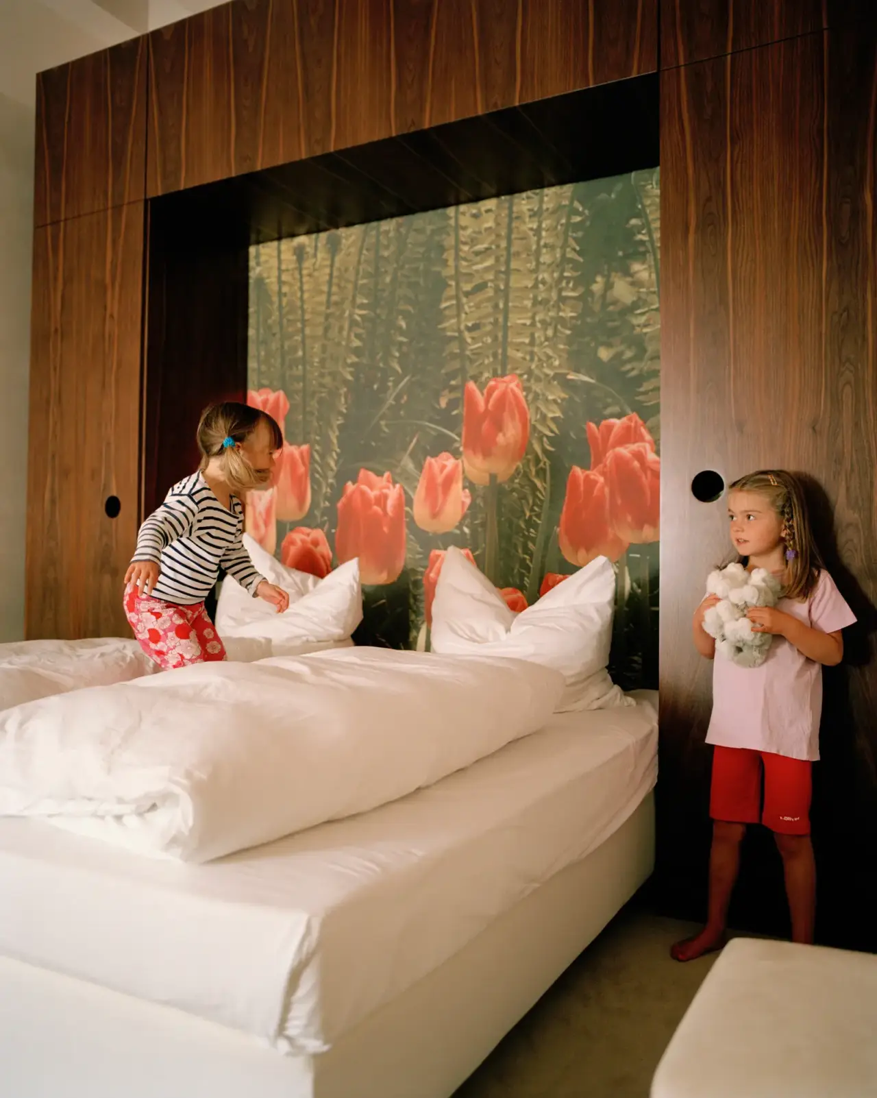 Hotelzimmer mit zwei Kindern auf dem Bett und floraler Wandgestaltung im Seehotel am Neuklostersee.