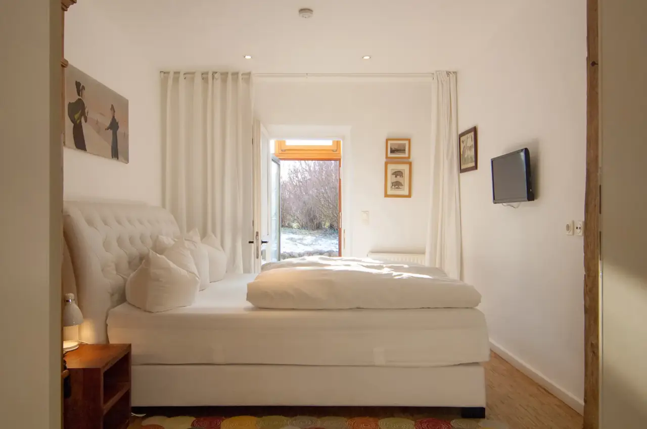 Helles, gemütliches Doppelzimmer mit weißem Boxspringbett und Blick in den Garten im Seehotel am Neuklostersee.