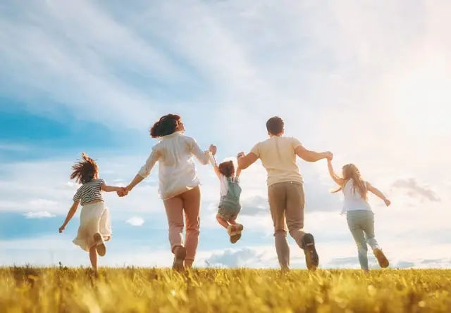 Familie mit Kindern läuft lachend und Hand in Hand über eine sonnige Wiese unter blauem Himmel, Kurhotel Hochsauerland 2010.