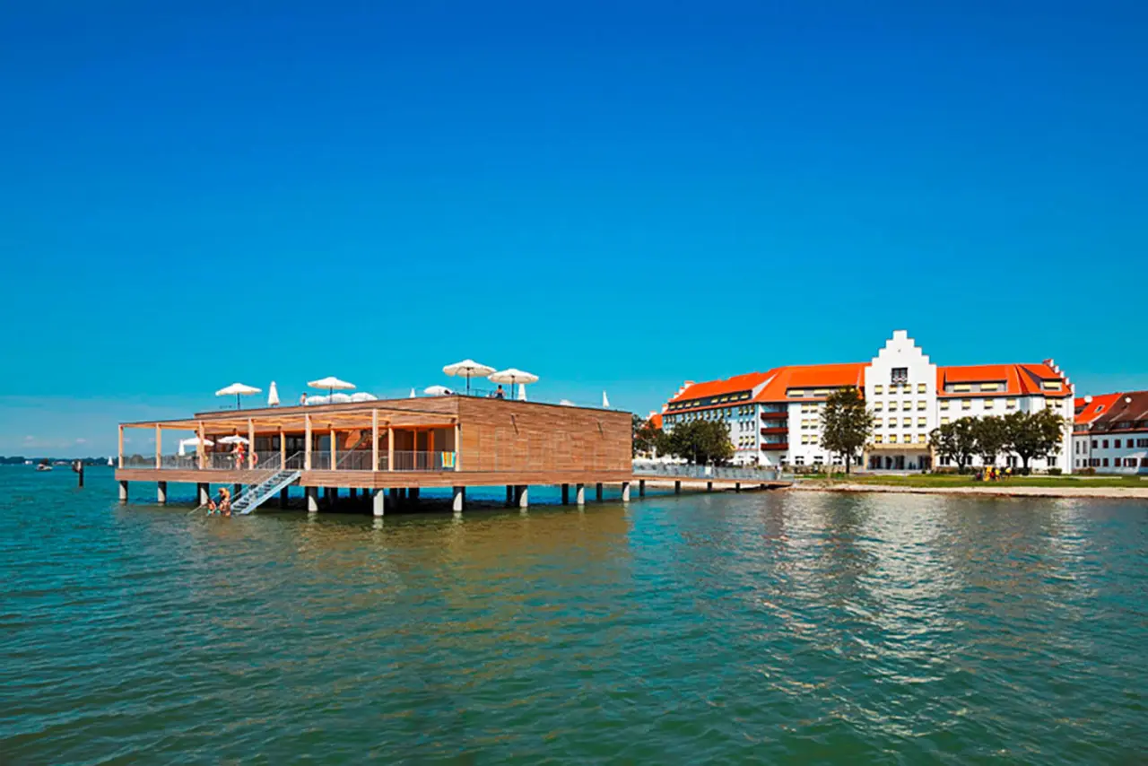 Seehotel Am Kaiserstrand mit historischem Hauptgebäude und modernem Badehaus direkt am Bodensee unter blauem Himmel.