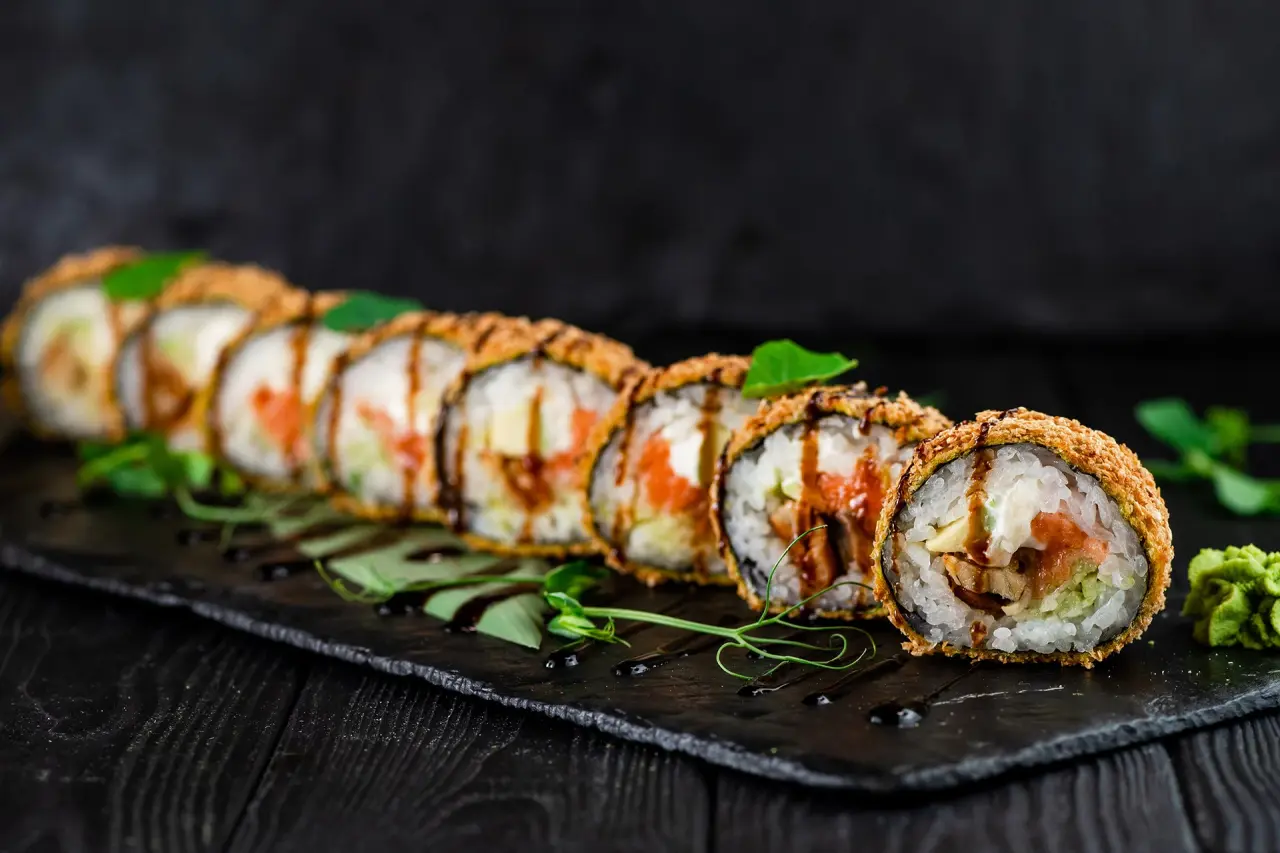 Knusprige Tempura Sushi Rollen mit Wasabi und Soße auf Schieferplatte im Restaurant des Seehotel Am Kaiserstrand.