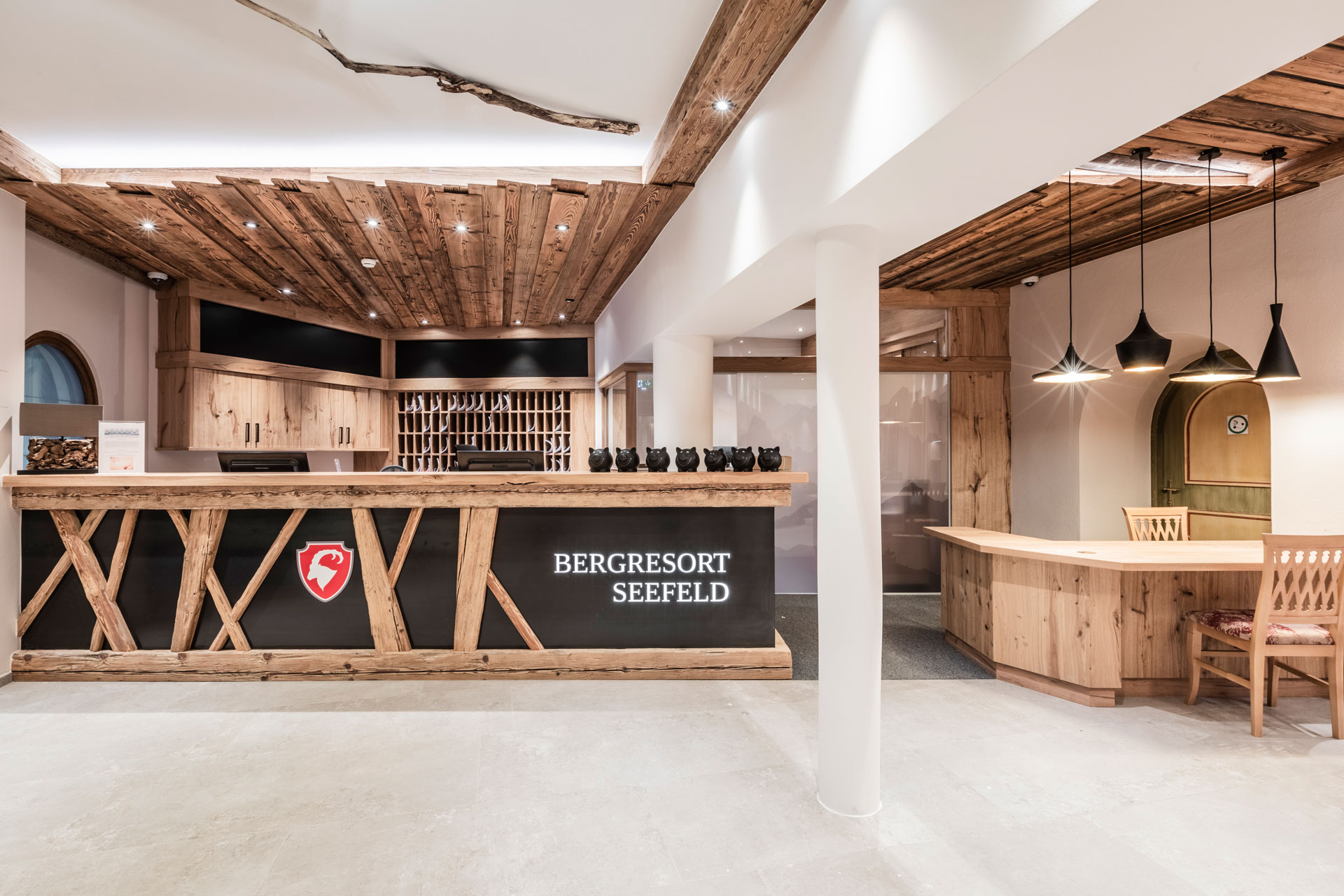 Bergresort Seefeld in Seefeld – Einladende Lounge mit rotem Sitzbereich und Holztischen | Wellnesshotel Tirol