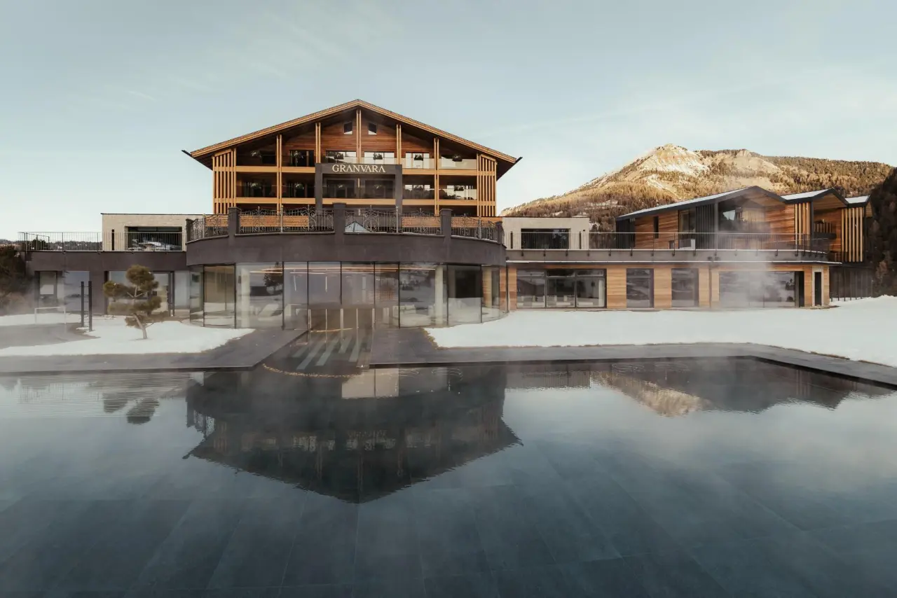 GRANVARA® Relais & SPA Hotel in Wolkenstein – Außenansicht mit beheiztem Pool und Bergpanorama | Wellnesshotel Gröden