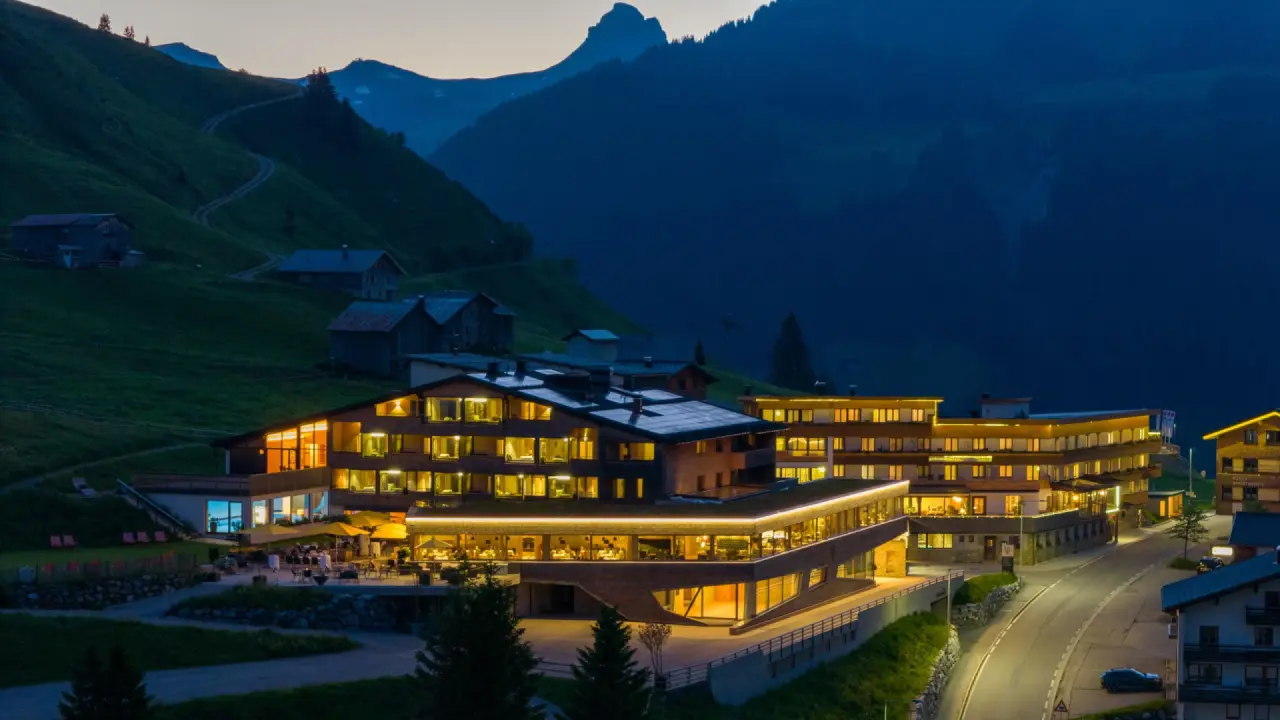Alpenresort Walsertal bei Dämmerung mit beleuchteten Fenstern und majestätischer Bergkulisse.