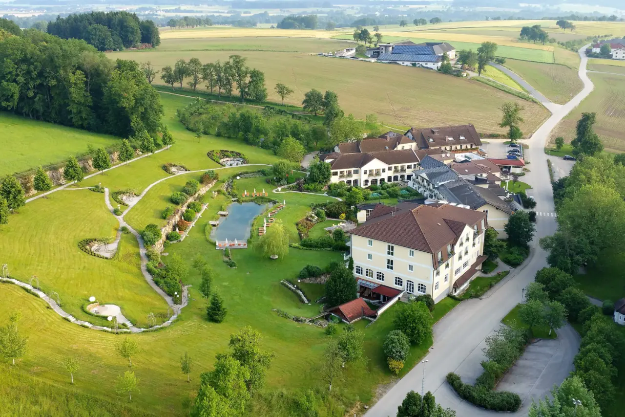 Luftaufnahme des RelaxResort Kothmühle mit Hotelgebäuden, großem Naturbadeteich und weitläufiger grüner Gartenanlage.