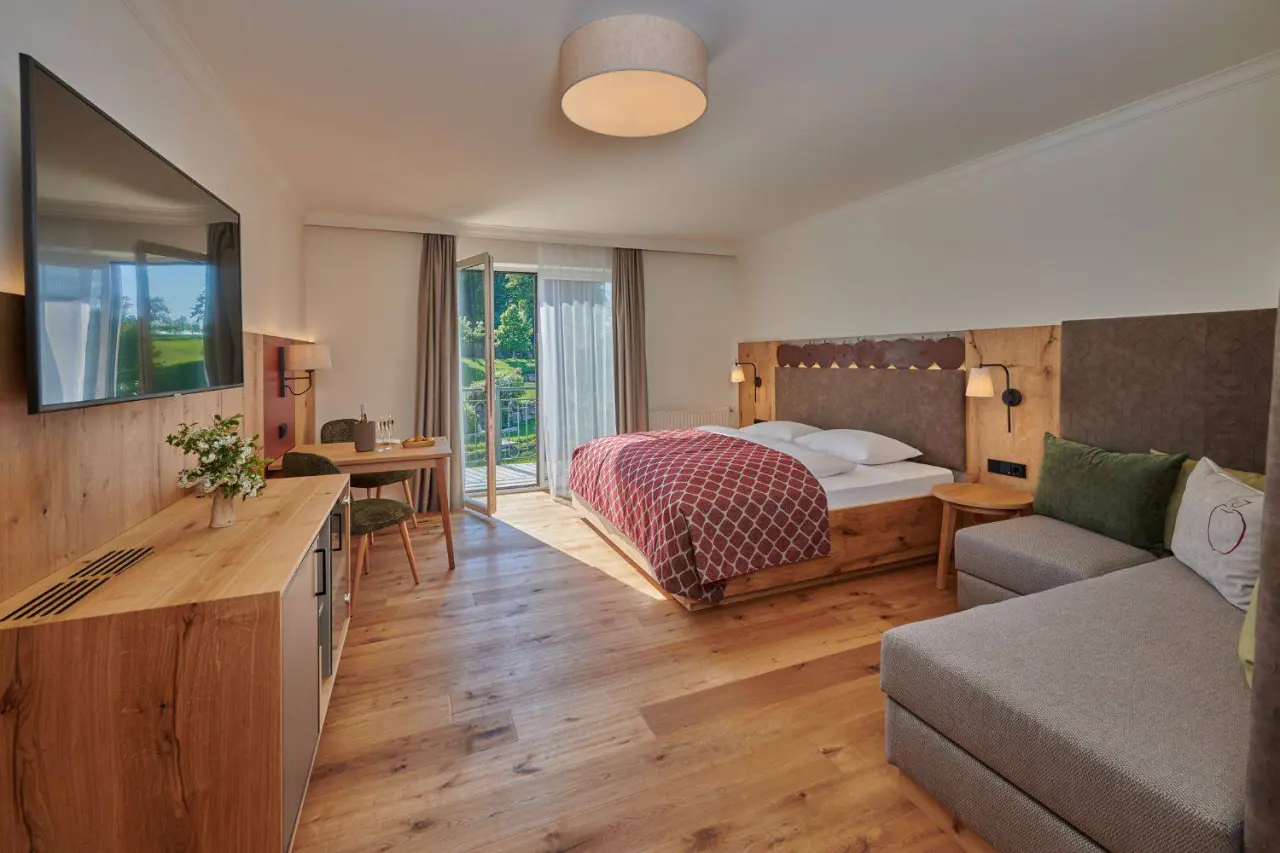Geräumiges Hotelzimmer im RelaxResort Kothmühle mit Doppelbett, Sitzbereich, TV und Balkonblick ins Grüne.
