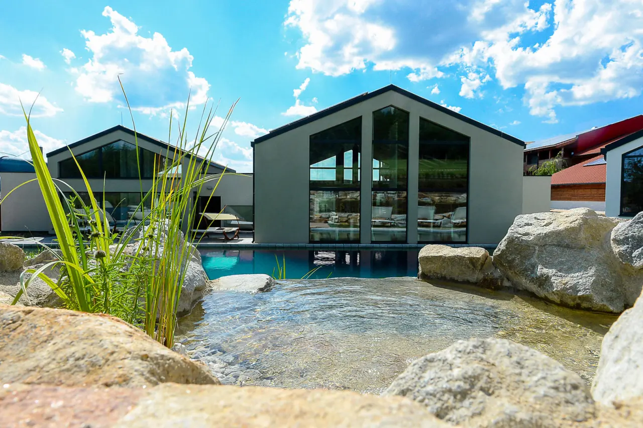 Modernes Outdoor-Pool-Areal mit Naturstein-Wasserlauf und moderner Architektur im Ulrichshof Baby & Kinder Bio-Resort.
