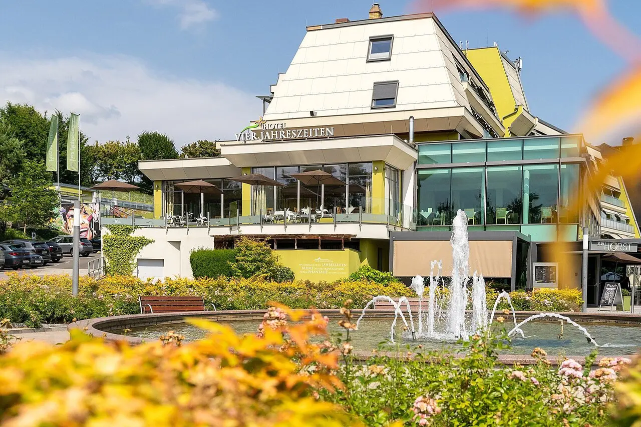Aussenansicht des Thermenhotel Vier Jahreszeiten Loipersdorf mit moderner Architektur, Terrasse und Springbrunnen.