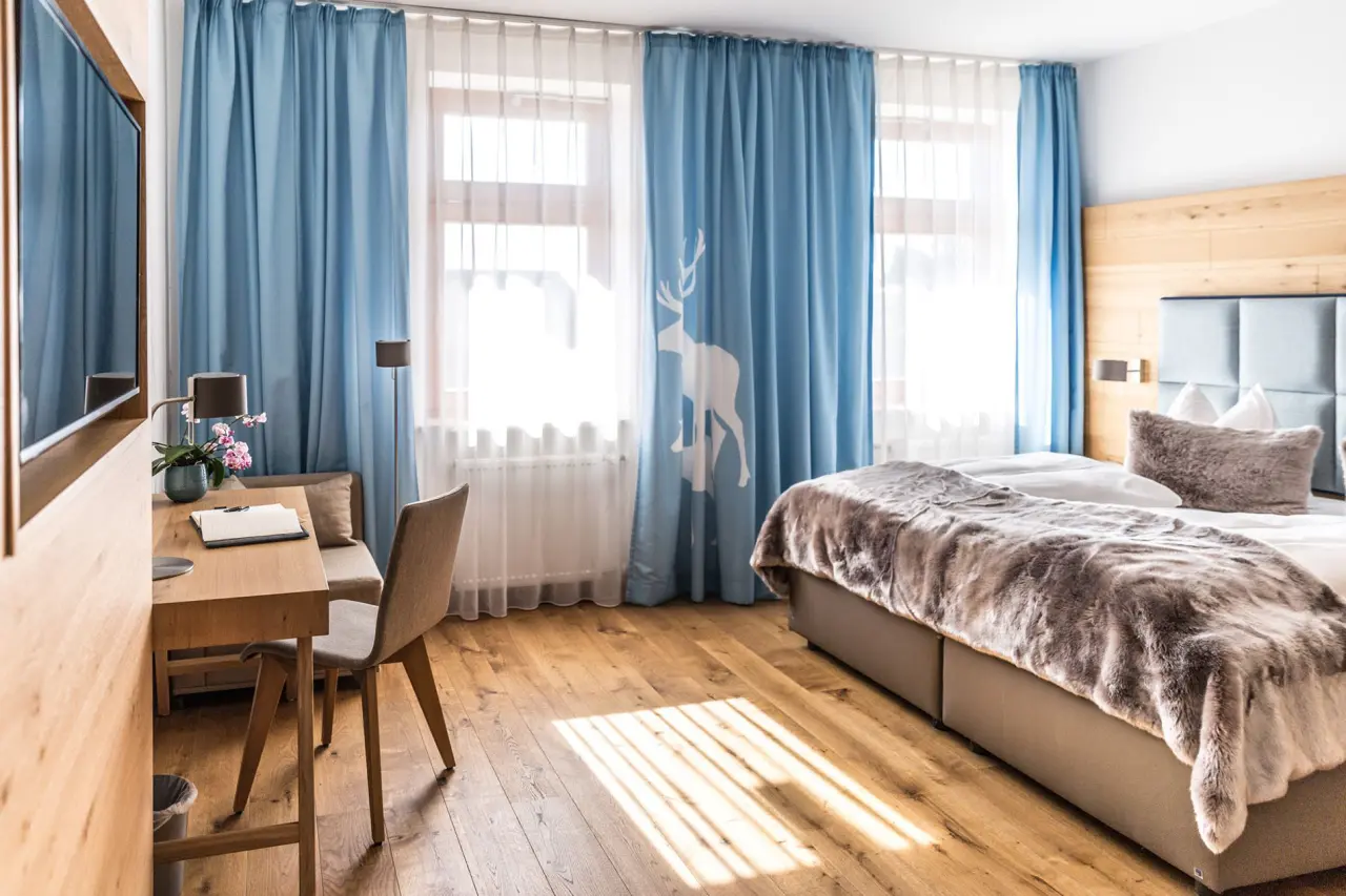 Gemütliches Hotelzimmer im Das Aunhamer mit Doppelbett, Schreibtisch und hellem Fensterbereich.