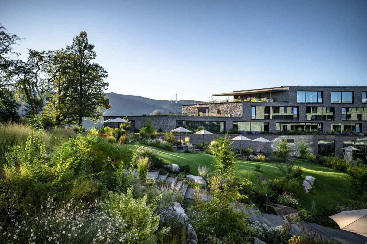 Moderne Architektur des Luisenhöhe Gesundheitsresort Schwarzwald eingebettet in eine grüne Gartenlandschaft mit Bergblick.