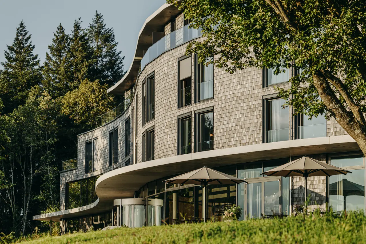 Moderne, geschwungene Architektur des Luisenhöhe Gesundheitsresorts Schwarzwald, umgeben von grünen Bäumen und Natur.