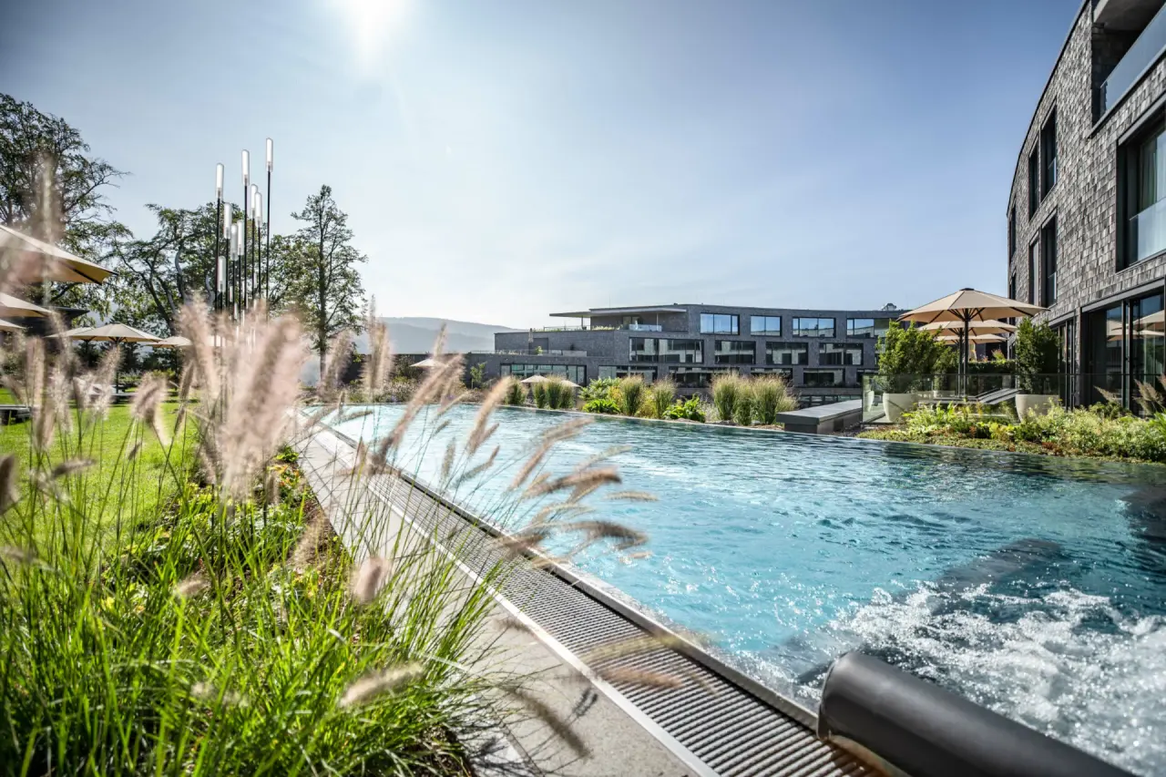 Aussenpool mit Sprudelfunktion und modernem Hotelgebäude der Luisenhöhe – Gesundheitsresort Schwarzwald bei Sonnenschein.