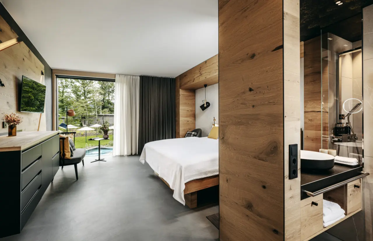 Modernes Hotelzimmer mit Holzelementen und direktem Blick auf den Aussenpool im Luisenhöhe – Gesundheitsresort Schwarzwald.