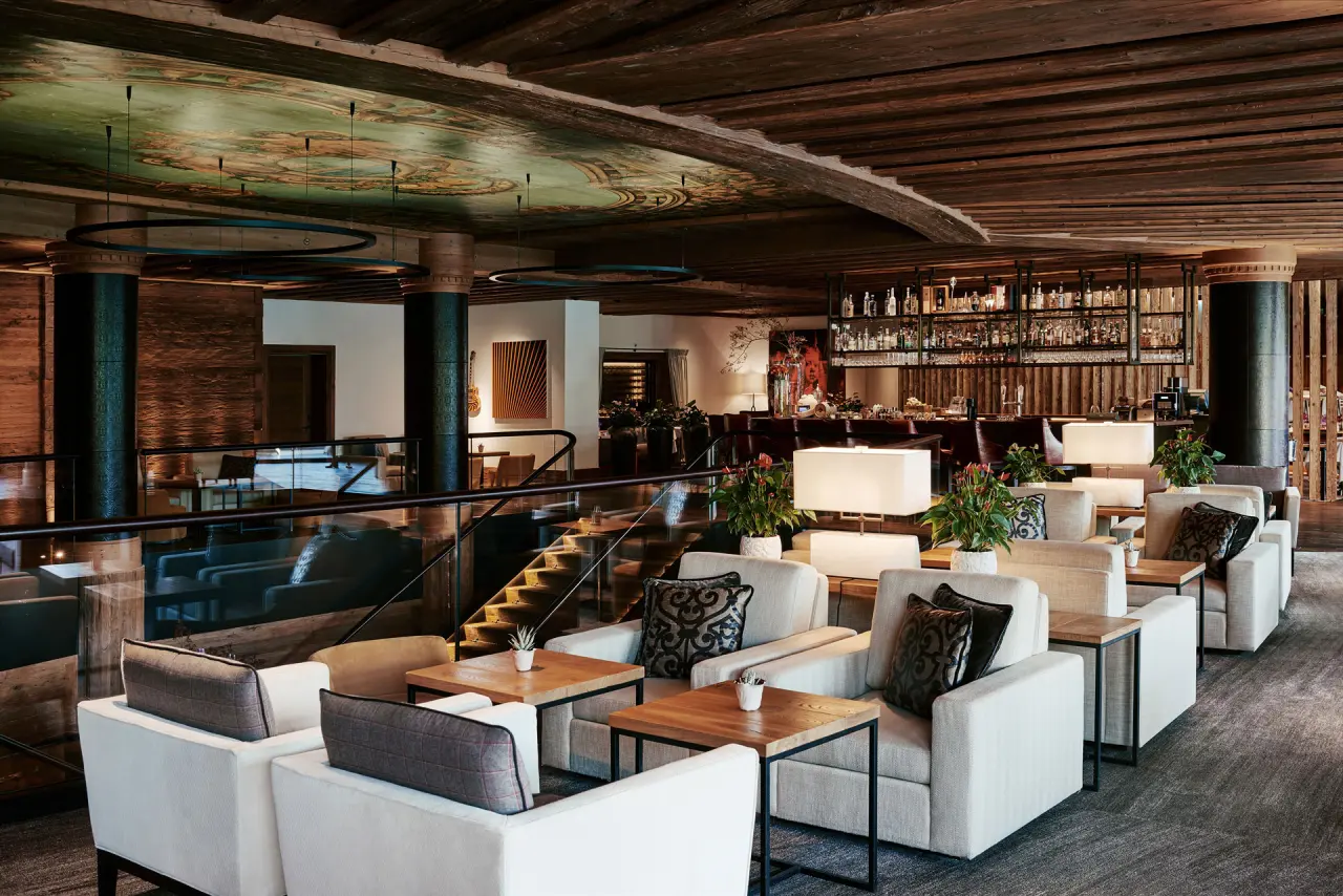 Elegante Hotelbar und Lounge im The Alpina Gstaad mit stilvollen Sitzbereichen und kunstvoller Deckenmalerei.